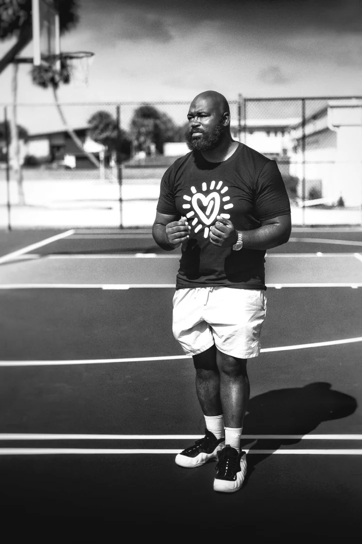 Black-and-white portrait of Gabriel standing on an outdoor basketball court.