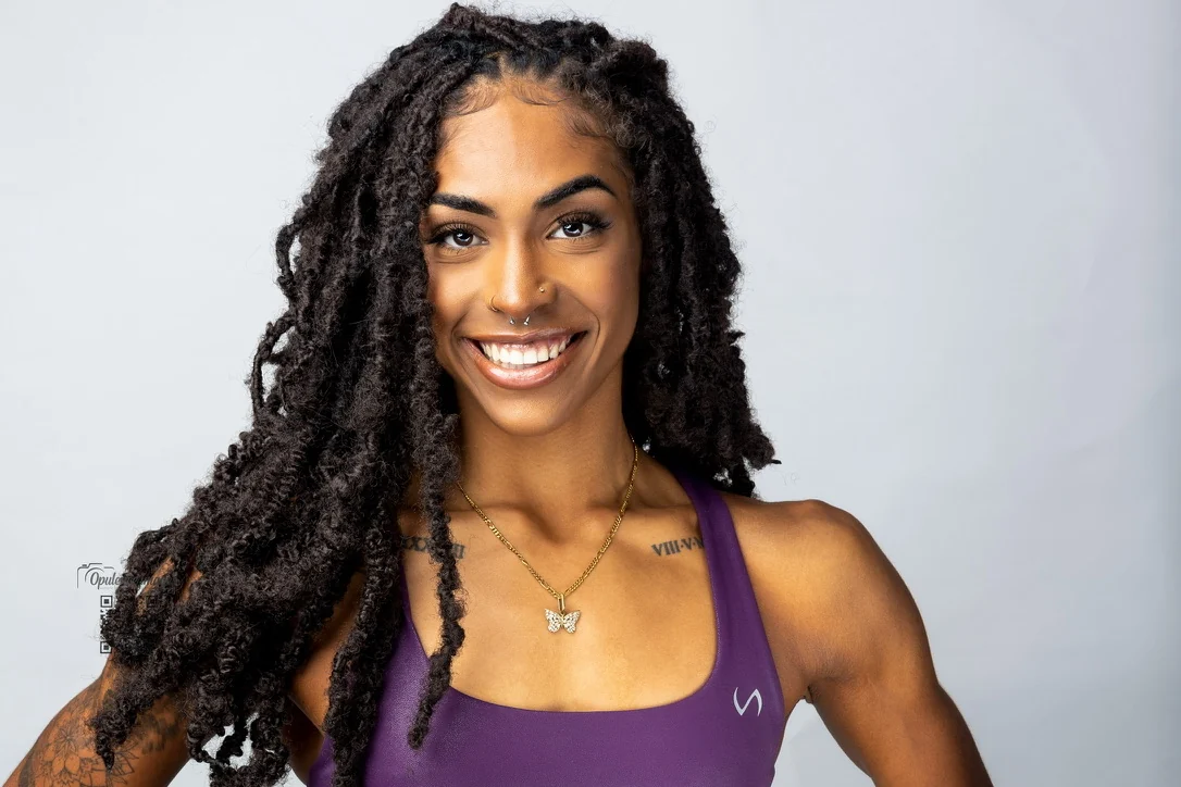 Smiling woman in purple activewear against a light studio background
