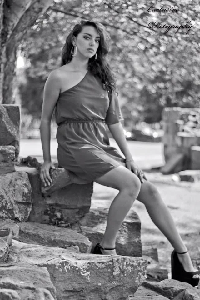 Black and white portrait of a woman seated on stone outdoors
