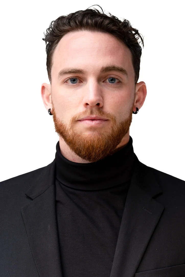 Studio headshot of a man in a black jacket and turtleneck