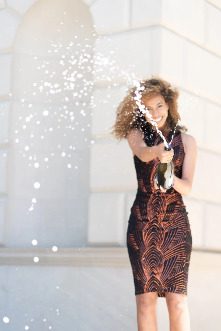Smiling woman spraying champagne outdoors