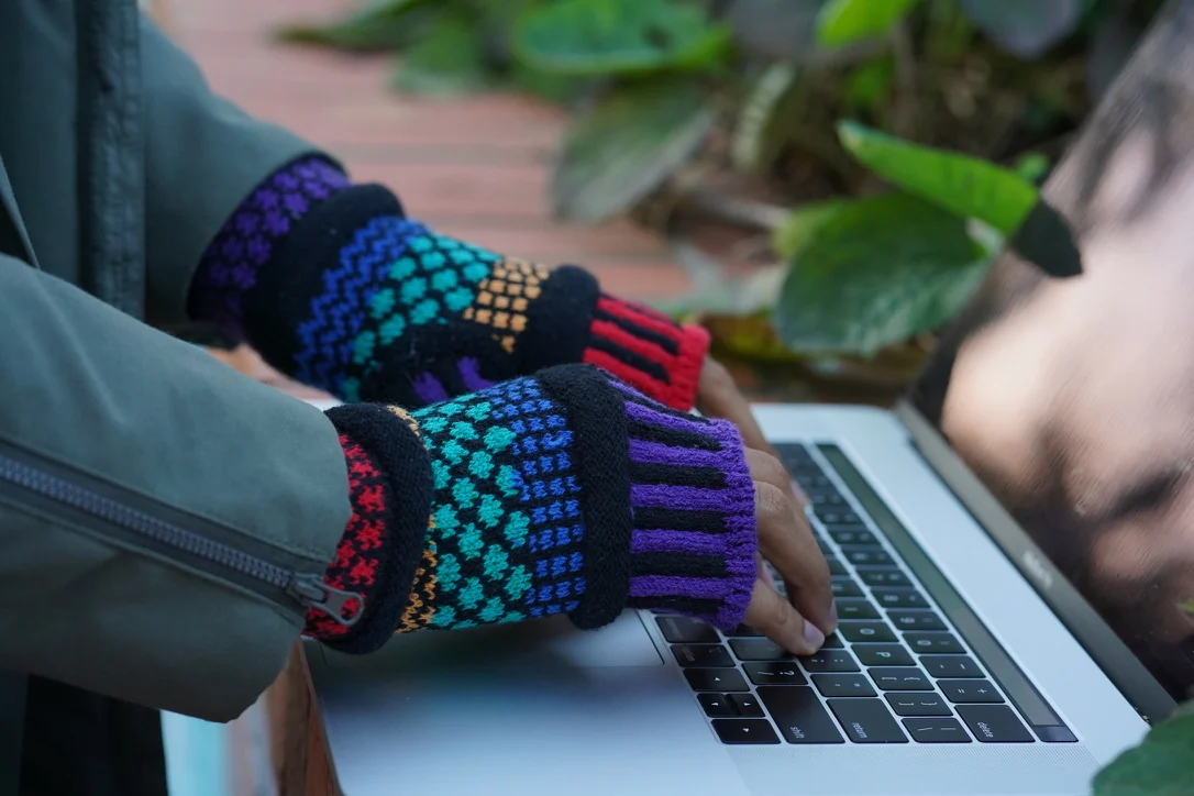 Colorful knitted wrist warmers worn while using a keyboard