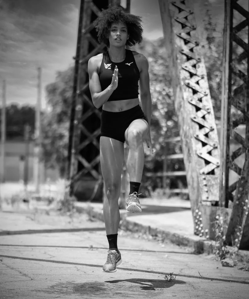 Black and white portrait of a runner beside an industrial structure